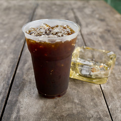 Delicious ice coffee americano  with cigarette on the old wooden