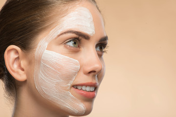 Beautiful girl in spa with cosmetic cream on her face