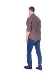 Back view of going  handsome man in jeans and a shirt.