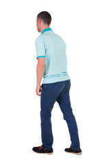 Back view of going  handsome man in jeans and a shirt.