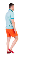 Back view of going  handsome man in shorts.  walking young guy