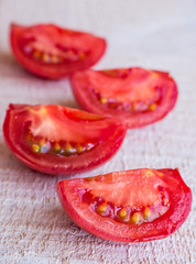 quarters of red tomatoes on a white wooden board