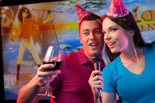 Young couple with microphone standing in bar.
