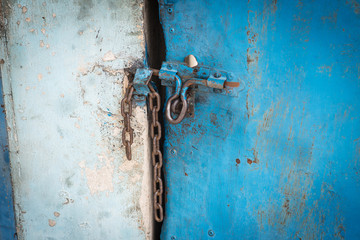Old blue steel door closed by a chain