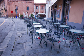 Fototapeta na wymiar Fila di tavolini e seggiole vuoti, caffe, gelateria, bar