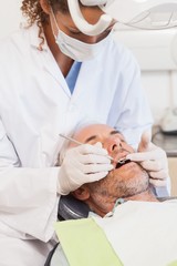 Obraz na płótnie Canvas Dentist examining a patients teeth in the dentists chair