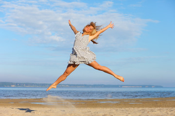 Beautiful young girl jumping on sea