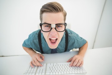 Casual angry businessman typing at his desk