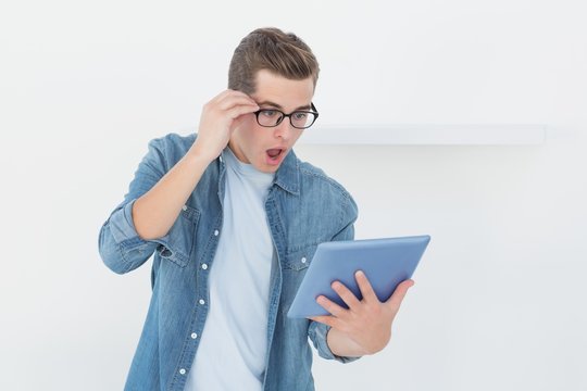 Nerdy casual businessman looking at tablet with shock