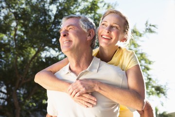 Happy senior man giving his partner a piggy back