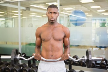 Fototapeta na wymiar Portrait of serious man lifting barbell in gym