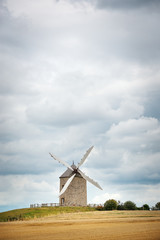Naklejka na ściany i meble Old windmill against cloudy sky. Brittany, France.