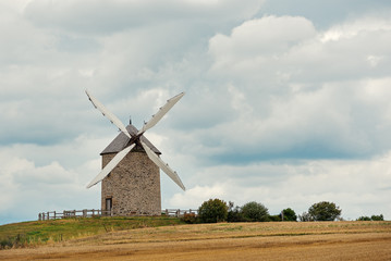 Fototapeta na wymiar Old windmill against cloudy sky. Brittany, France.