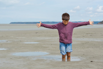 Young kid having fun with quicksand on the beach in front of Mon - obrazy, fototapety, plakaty