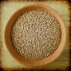 Buckwheat in clay bowl on old paper background