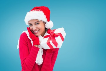 Composite image of festive brunette holding gift