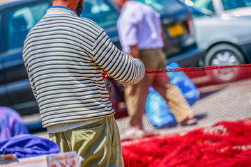 Sailor repairing the red fishing net