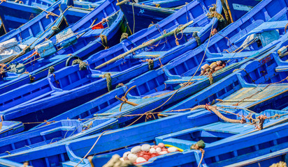Many blue fishing boats tried next to one another