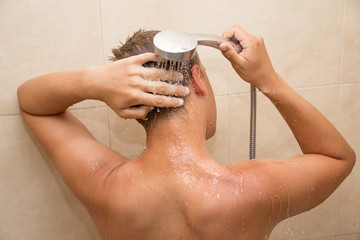 back view of young man washing head in bathroom
