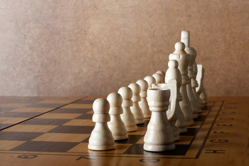 Wooden chess board with figures on green table and old wall