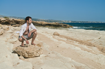 Fototapeta na wymiar man sitting on rock looking at sea