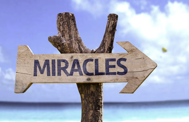 Miracles wooden sign with a beach on background