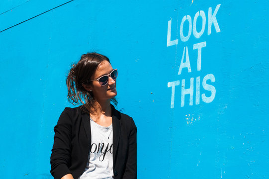 Hipster model wearing sunglasses posing next to "Look at This"