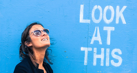Portrait of a model wearing sunglasses next to a blue wall
