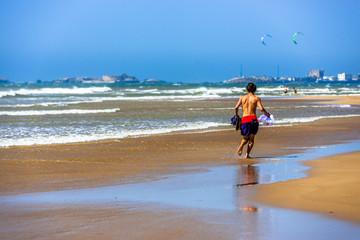 A man in swimming shorts runing along the beach