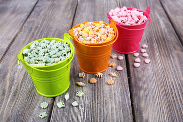Beads in metal buckets on wooden background