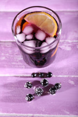 Glass of cold berry cocktail on wooden background