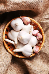 Fresh garlic in wicker basket, on wooden background