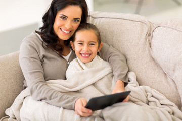 woman and her little daughter snuggle on couch