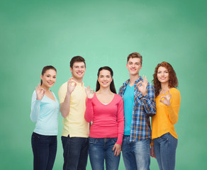 group of smiling teenagers over green board