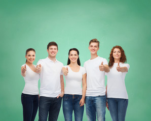 smiling teenagers in t-shirts showing thumbs up