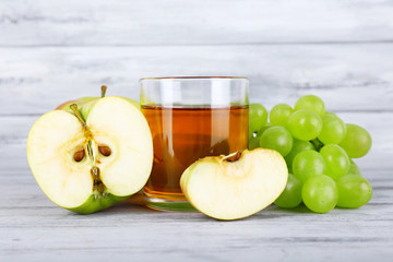 glass of juice with fresh grape and apples on grey wooden table
