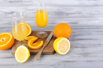 glasses of juice with fresh fruits on grey wooden table