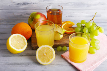 glasses of juice with fresh fruits on grey wooden table