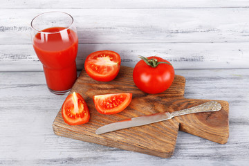 glass of tasty tomato juice and fresh tomatoes on wooden table
