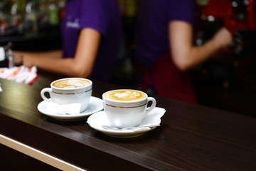 Cups of coffee with cute drawing in cafe