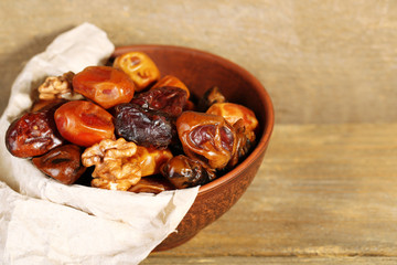 Tasty dates fruits in bowl, on wooden background