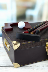 Golf set in suitcase on table on bright background