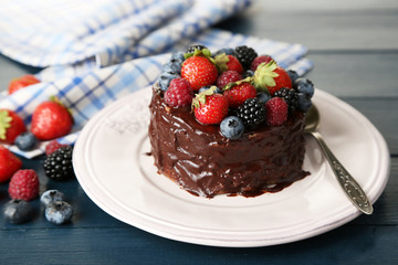 Tasty chocolate cake with different berries, on wooden table