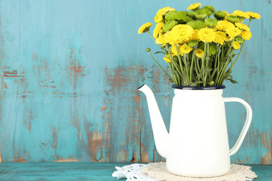 Yellow and green flowers in decorative teapot