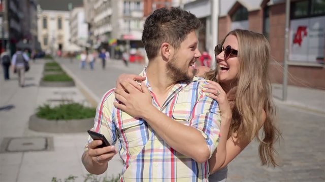 Happy woman surprises waiting man by covering his eyes
