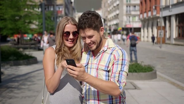 Attractive couple taking self-portrait with phone in a city