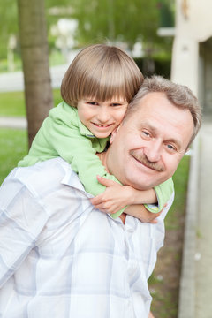 The Grandad Play With Grandson In City Park On Sunny Day