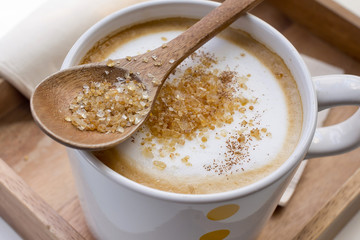 Brown sugar on a spoon and a cup of coffee Cappuccino