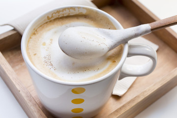 Whipping Cream on a spoon and a cup of coffee Cappuccino