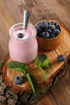 yogurt with blueberries in a glass jar and blueberries in a wood